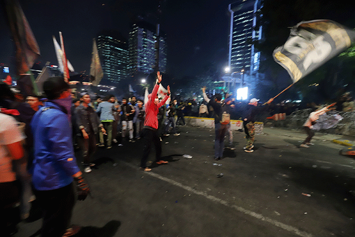 Sejumlah pengunjuk rasa berusaha membakar pembatas jalan saat aksi di kawasan Jalan Medan Merdeka Barat, Jakarta, Selasa (13/9/2022).
