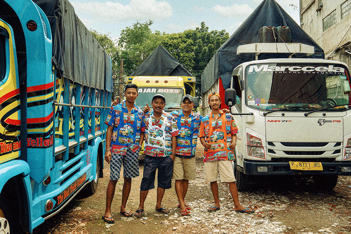 Sejumlah sopir berpose mengenakan pakaian bermotif yang diangkat dari ragam lukisan di belakang truk dan angkutan, Rabu (21/9/2022).