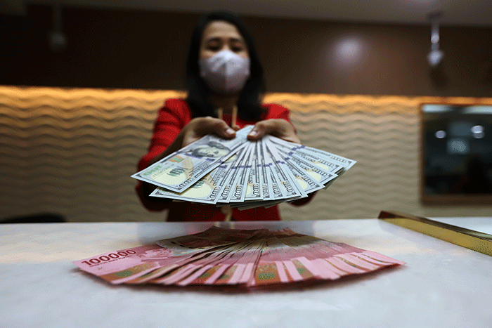 Petugas menunjukan uang pecahan dolar dan rupiah di Jakarta, Senin (3/10/2022).