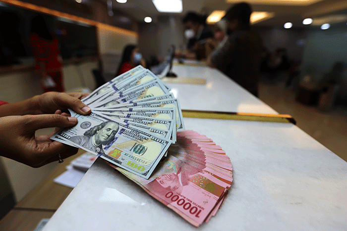 Petugas menunjukan uang pecahan dolar dan rupiah di Jakarta, Senin (3/10/2022).