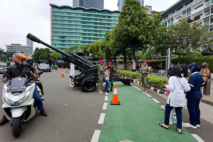 Warga berfoto di depan sejumlah alat utama sistem persenjataan atau alutsista milik TNI yang dipamerkan didepan Istana dan Bundaran Hotel Indonesia.