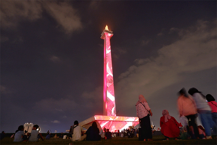 Pengunjung menyaksikan pertunjukkan video mapping dan air mancur menari pada acara Monas Week 2022 di kawasan Monas, Jakarta, Minggu (16/10/2022).