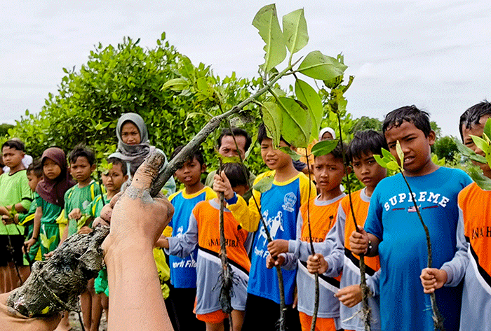 Para anggota Jurnalis Mancing Indonesia bersama anak anak sekolah dasar menanam bibit pohon mangrove di desa Ambulu, Kecamatan Losari, Kabupaten Cirebon.