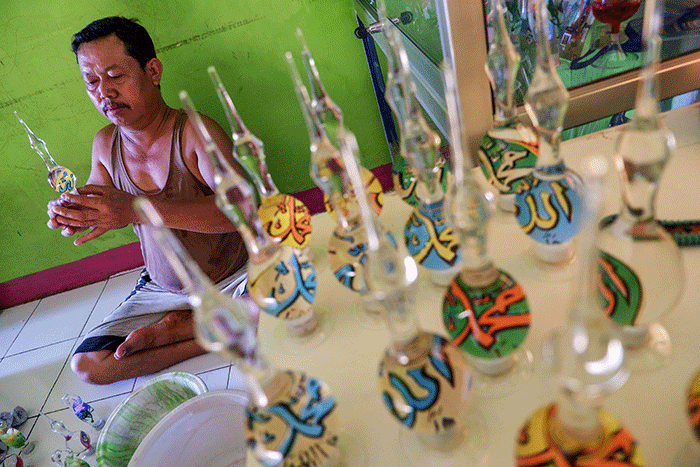 Pengrajin UMKM menyelesaikan pembuatan produk daur ulang lampu bekas menjadi neon kreasi di rumah produksi Dua Putri Souvenir Glass.