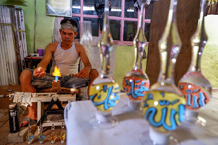Pengrajin UMKM menyelesaikan pembuatan produk daur ulang lampu bekas menjadi neon kreasi di rumah produksi Dua Putri Souvenir Glass.