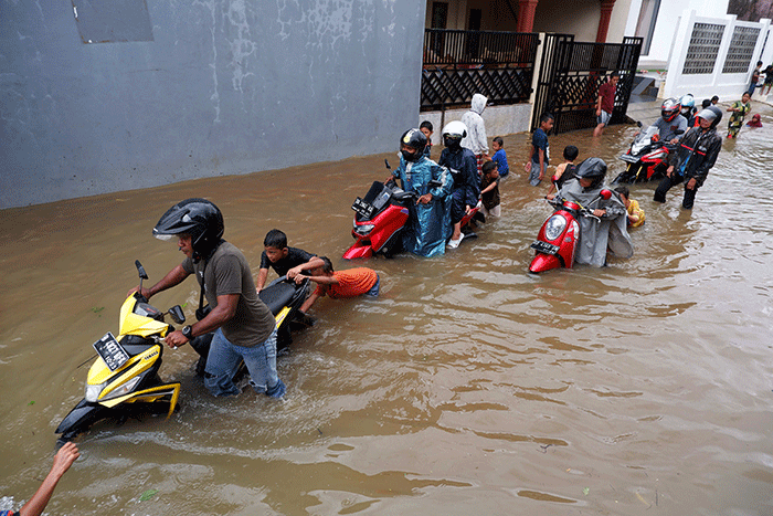 Warga melintasi banjir yang mengenangi Jalan Nipa-nipa di Kecamatan Manggala, Makassar, Sulawesi Selatan, Minggu (20/11/2022).