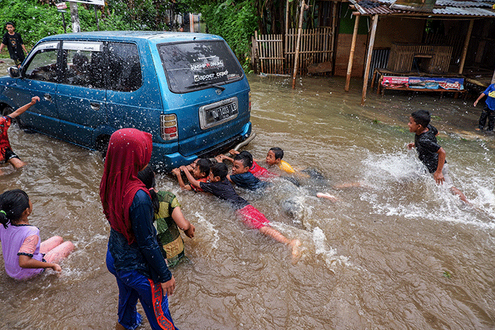 Warga melintasi banjir yang mengenangi Jalan Nipa-nipa di Kecamatan Manggala, Makassar, Sulawesi Selatan, Minggu (20/11/2022).