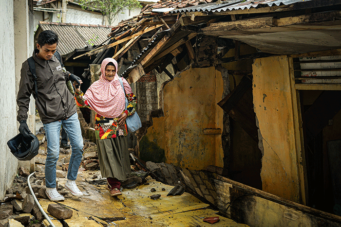 Seorang warga berfoto di depan rumah miliknya yang hancur akibat gempa di Kampung Barukaso, Desa Sukamulya, Kabupaten Cianjur, Jawa Barat, Rabu (23/11/2022).