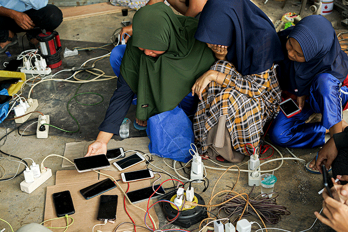 Sejumlah warga bergantian untuk mengisi daya ponselnya menggunakan genset keliling karena listrik masih padam imbas gempa bumi.