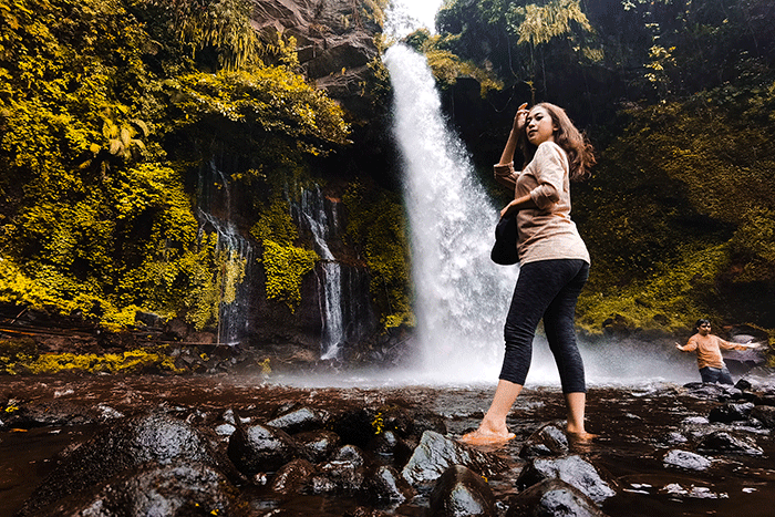 Pengunjung saat menikmati suasana keindahan air terjun curug Telu di lereng Gunung Slamet, Jawa Tengah, Minggu (27/11/2022).
