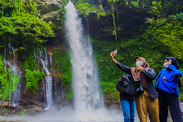 Pengunjung saat menikmati suasana keindahan air terjun curug Telu di lereng Gunung Slamet, Jawa Tengah, Minggu (27/11/2022).