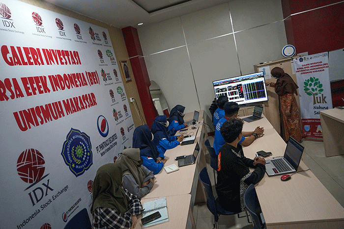 Warga tengah membuka situs Bursa Efek Indonesia untuk membuka tabungan saham syariah di Pantai Losari, Makassar.