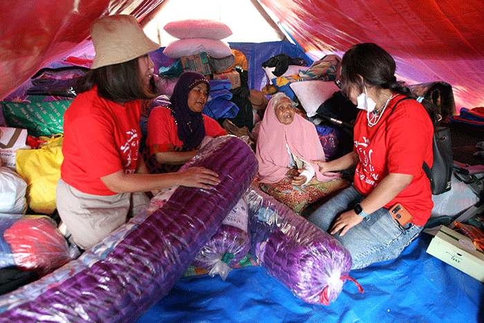 Volunteer Karyawan Prudential Indonesia berbincang dengan korban gempa usai membagikan bantuan di Desa Sukamulya, Cugenang, Kabupaten Cianjur.