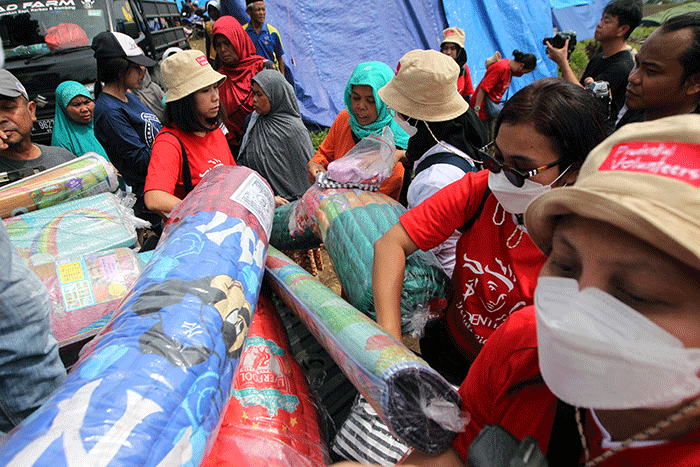 Volunteer Karyawan Prudential Indonesia berbincang dengan korban gempa usai membagikan bantuan di Desa Sukamulya, Cugenang, Kabupaten Cianjur.
