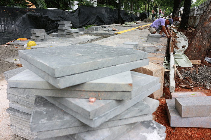 Pekerja saat menyelesaikan proyek revitalisasi trotoar di kawasan Jalan Medan Merdeka, Jakarta, Selasa (6/12/2022).