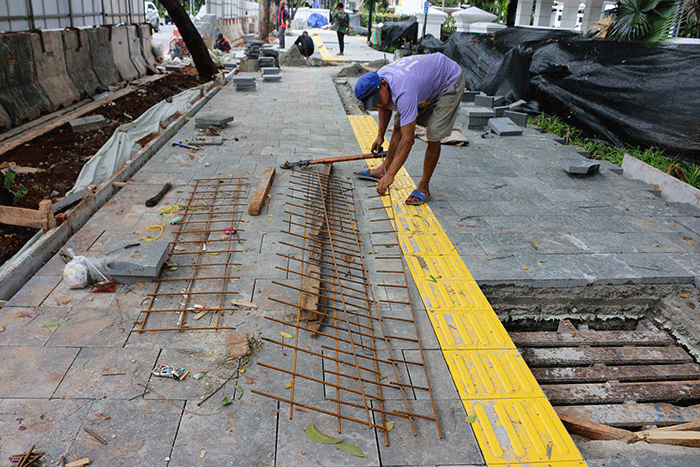 Pekerja saat menyelesaikan proyek revitalisasi trotoar di kawasan Jalan Medan Merdeka, Jakarta, Selasa (6/12/2022).