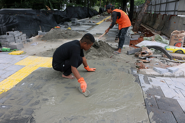Pekerja saat menyelesaikan proyek revitalisasi trotoar di kawasan Jalan Medan Merdeka, Jakarta, Selasa (6/12/2022).