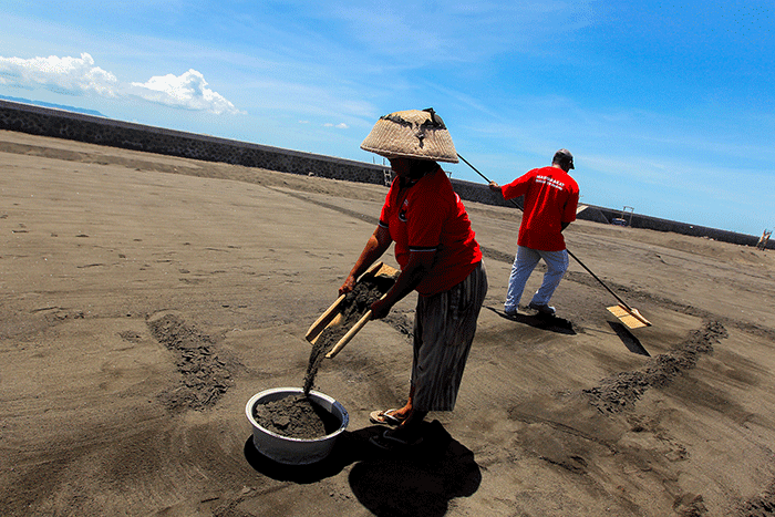 Petani saat merapikan ladang garam setelah disiram air laut di Desa Kusamba, Bali, Selasa (20/12/2022).