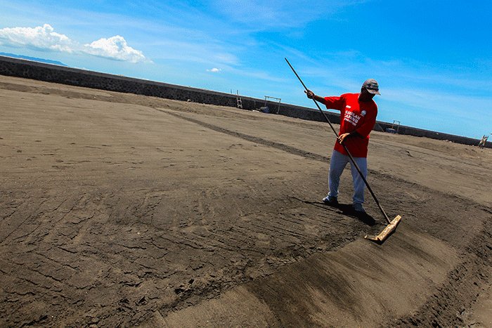 Petani saat merapikan ladang garam setelah disiram air laut di Desa Kusamba, Bali, Selasa (20/12/2022).