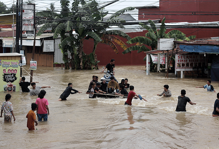 Sejumlah warga melewati banjir di Jalan Poros Nipa Nipa Antang, Makassar, Minggu (25/12/2022).