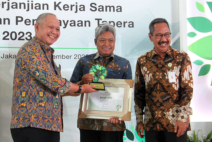 Direktur Consumer Bank BTN Hirwandi Gafar (kedua kanan) menunjukkan naskah perjanjian kerja sama penyaluran KPR Sejahtera FLPP dan Pembiayaan Tapera.