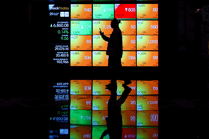 Karyawan melintas di depan layar pergerakan Indeks Harga Saham Gabungan (IHSG) di Bursa Efek Indonesia (BEI), Jakarta, Kamis (29/12/2022).