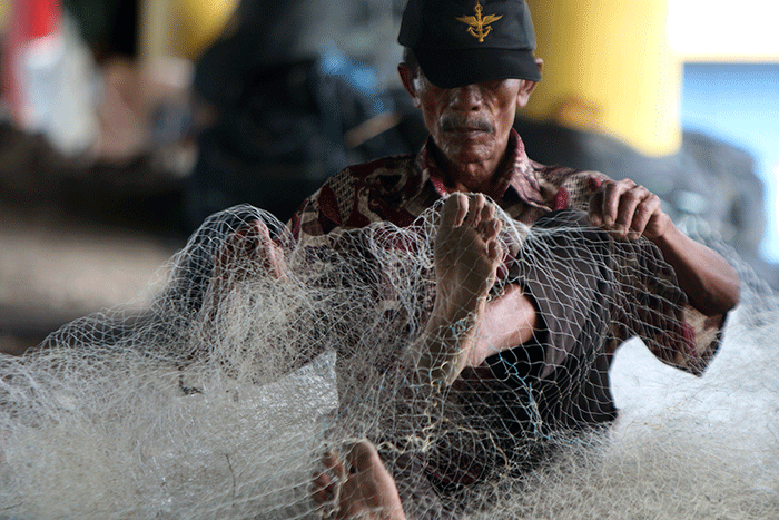 Nelayan memperbaiki jaring yang rusak di Kampung Nelayan Cilincing, Jakarta, Jumat (30/12/2022).