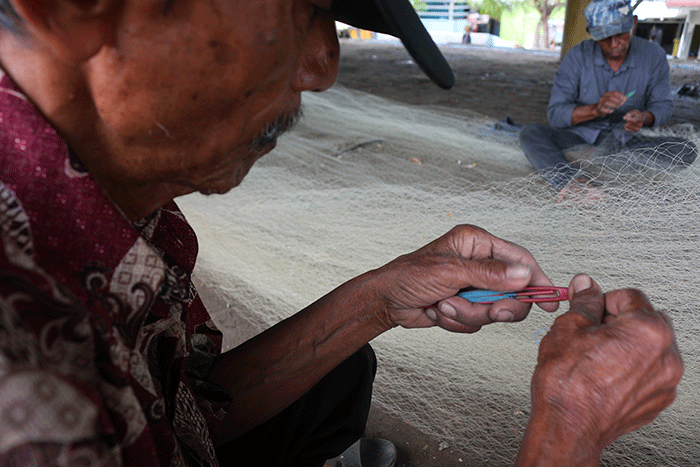 Nelayan memperbaiki jaring yang rusak di Kampung Nelayan Cilincing, Jakarta, Jumat (30/12/2022).