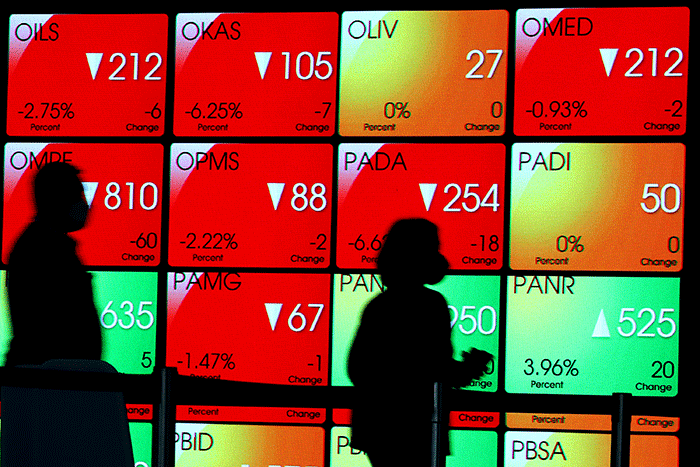 Karyawan melintasi layar yang menampilkan Indeks Harga Saham Gabungan (IHSG) saat acara Penutupan Perdagangan Bursa Efek Indonesia Tahun 2022 di Jakarta.