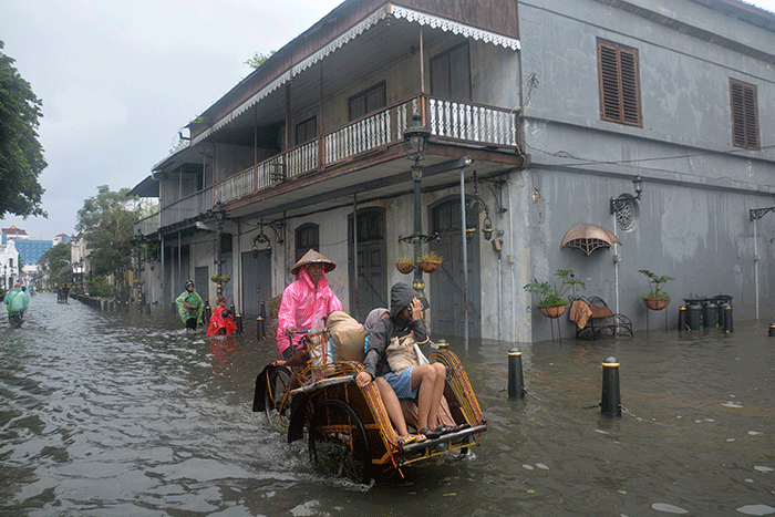 Sejumlah warga menerjang banjir yang merendam kawasan Kota Lama Semarang, Jawa Tengah, Sabtu (31/12/2022).
