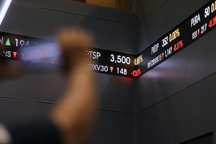 Pekerja melintasi Layar pergerakan Indeks Harga Saham Gabungan (IHSG) di Gedung Bursa Efek Indonesia, Jakarta, Senin (2/1/2023).