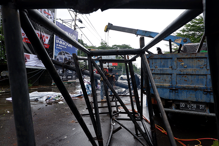 Sejumlah pekerja mengangkat reklame yang tumbang di perempatan Jalan Metro Tanjung Bunga, Makassar, Rabu (4/1/2023).