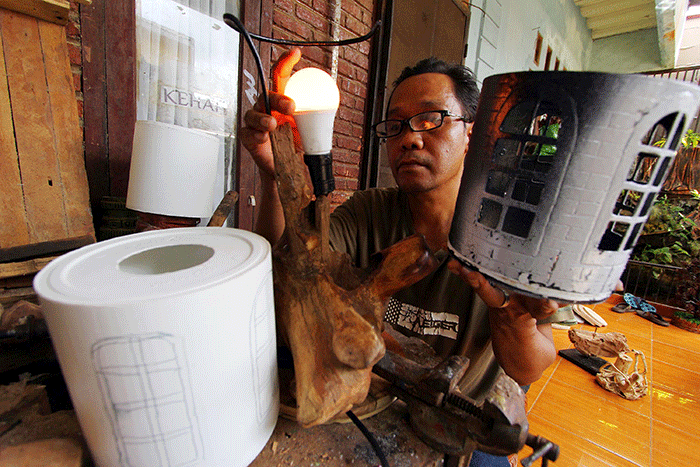 Perajin menyelesaikan pembuatan lampu hias dengan berbahan baku sampah plastik atau plastik tempat cat juga limbah kayu di kawasan Pamulang, Tangerang Selatan.