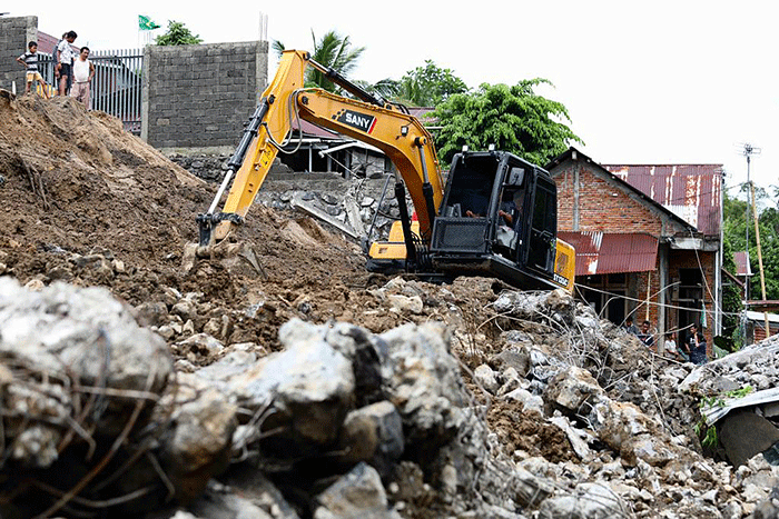 Warga dan petugas melakukan pembersihan, termasuk puing-puing sisa material bangunan yang rusak akibat tanah longsor di Kota Manado.
