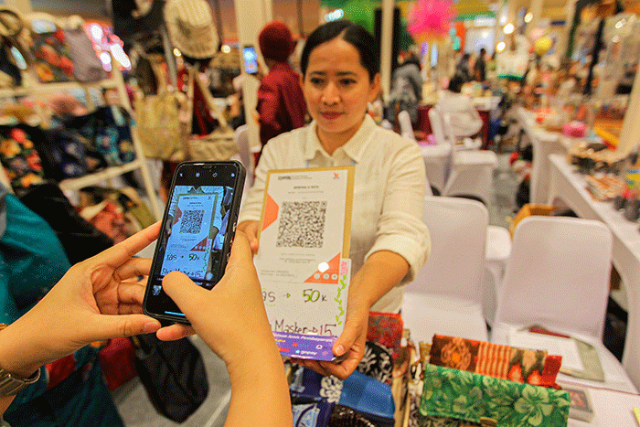 Pembeli membayar menggunakan QRIS dalam acara pameran UMKM di Jakarta, Jumat (3/2/2023).