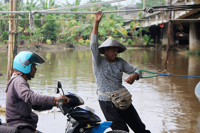 Sejumlah pengendara motor menggunakan jasa perahu eretan di kawasan Kali Angke, Jakarta, Sabtu (4/2/2023).