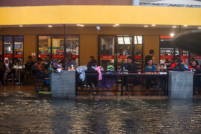 Sejumlah pengendara menerobos banjir yang menutupi jalan protokol pusat Kota Makassar, Senin (13/2/2023).