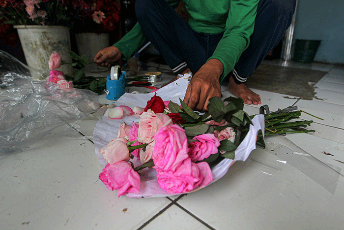 Penjual bunga saat membuat pesanan bucket mawar di Jalan Raya Pondok Gede, Jakarta Timur, Selasa (14/2/2023).