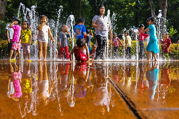 Anak-anak asik bermain air mancur di Taman Puring, Jakarta, Minggu (19/2/2023).
