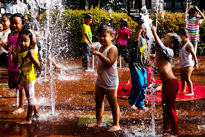 Anak-anak asik bermain air mancur di Taman Puring, Jakarta, Minggu (19/2/2023).