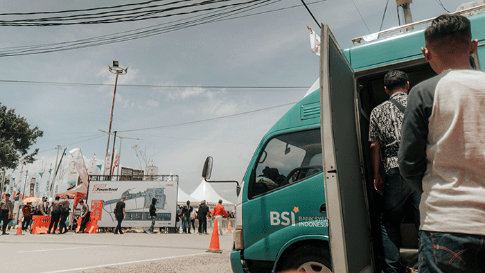 Pengunjung arena F1 PowerBoat melakukan transaksi perbankan di mobil kas keliling PT Bank Syariah Indonesia Tbk (BSI) di kawasan Danau Toba, Balige.