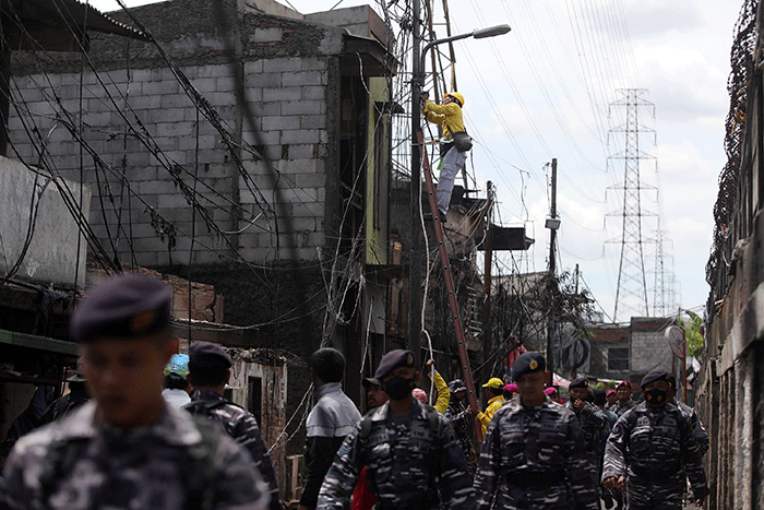 Petugas Suku Dinas Bina Marga Jakarta Utara memperbaiki fasilitas lampu penerangan jalan di permukiman penduduk yang hangus terbakar.