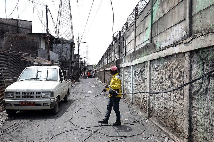 Petugas Suku Dinas Bina Marga Jakarta Utara memperbaiki fasilitas lampu penerangan jalan di permukiman penduduk yang hangus terbakar.
