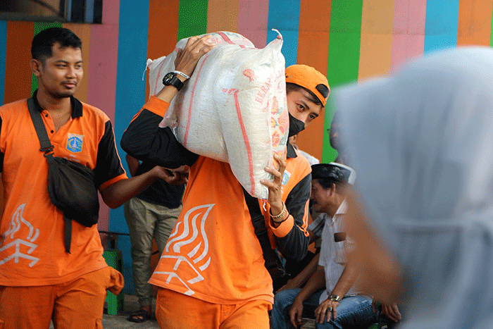 Warga menerima bantuan beras seberat 10 kg di kawasan Serdang Kemayoran, Jakarta, Sabtu (18/3/2023).