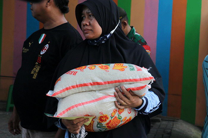 Warga menerima bantuan beras seberat 10 kg di kawasan Serdang Kemayoran, Jakarta, Sabtu (18/3/2023).