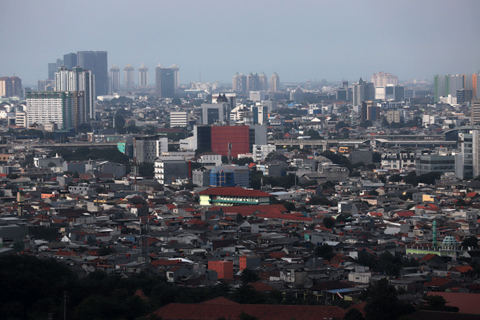 Pekerja melihat permukiman warga dan gedung bertingkat di Jakarta, Jumat (24/3/2023).