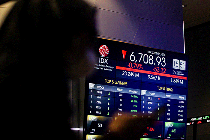 Pekerja berdiri di depan layar pergerakan Indeks Harga Saham Gabungan (IHSG) di Bursa Efek Indonesia (BEI), Jakarta, Senin (27/3/2023).