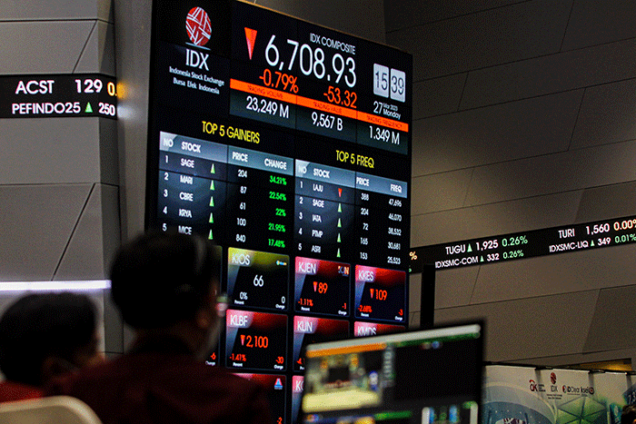 Pekerja berdiri di depan layar pergerakan Indeks Harga Saham Gabungan (IHSG) di Bursa Efek Indonesia (BEI), Jakarta, Senin (27/3/2023).