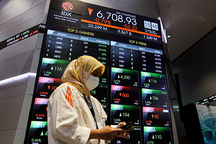 Pekerja berdiri di depan layar pergerakan Indeks Harga Saham Gabungan (IHSG) di Bursa Efek Indonesia (BEI), Jakarta, Senin (27/3/2023).