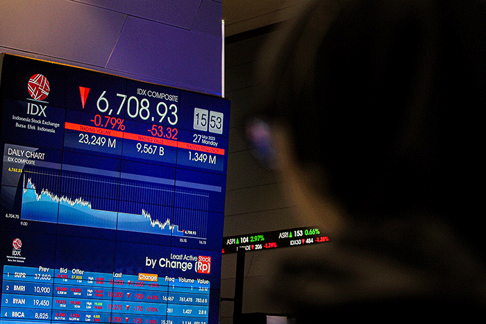 Pekerja berdiri di depan layar pergerakan Indeks Harga Saham Gabungan (IHSG) di Bursa Efek Indonesia (BEI), Jakarta, Senin (27/3/2023).